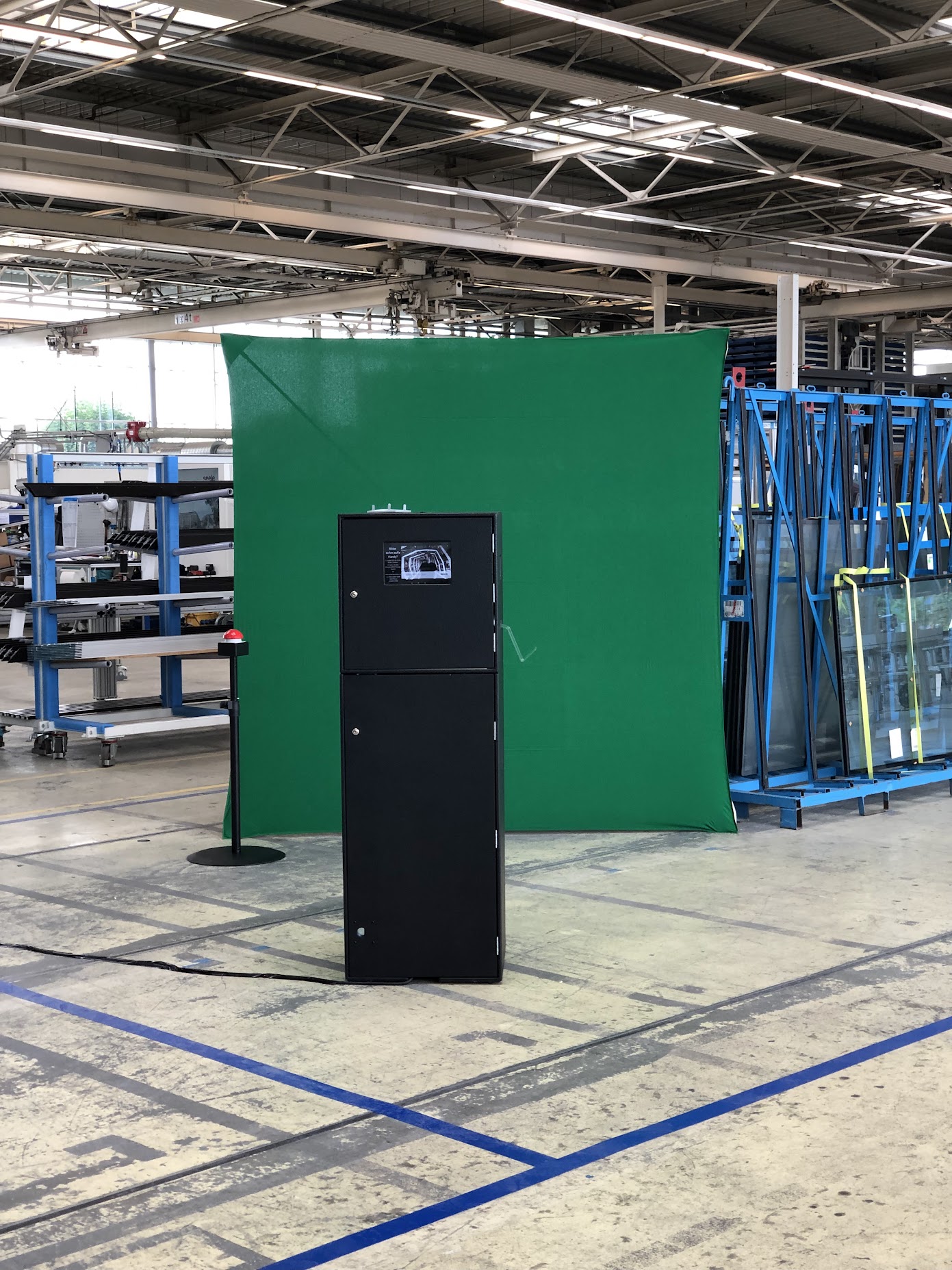 GiuGiu Fotobox mit rotem Buzzer vor großem Green Screen, aufgebaut mitten in der Glasproduktion bei seele in Gersthofen