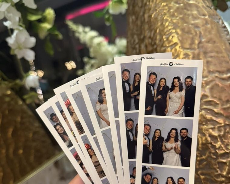 Hand hält frisch gedruckte GiuGiu-Fotostreifen einer Hochzeit
