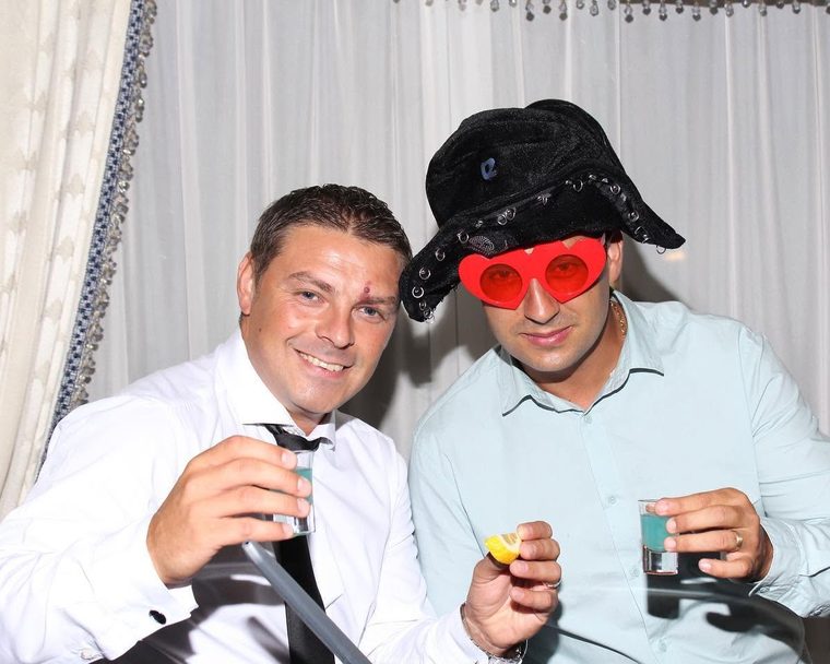 Zwei Gäste mit Riesenbrille und Hut albern vor der Fotobox